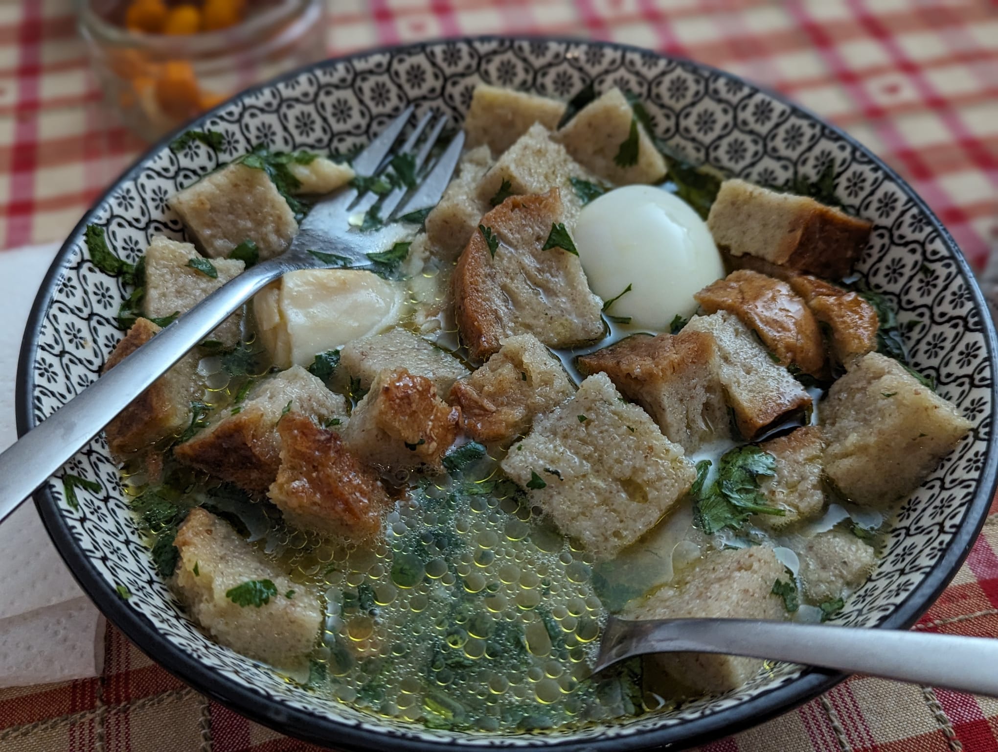 Açorda alentejana com ovo escalfado, coentros e azeite, servida numa tigela tradicional