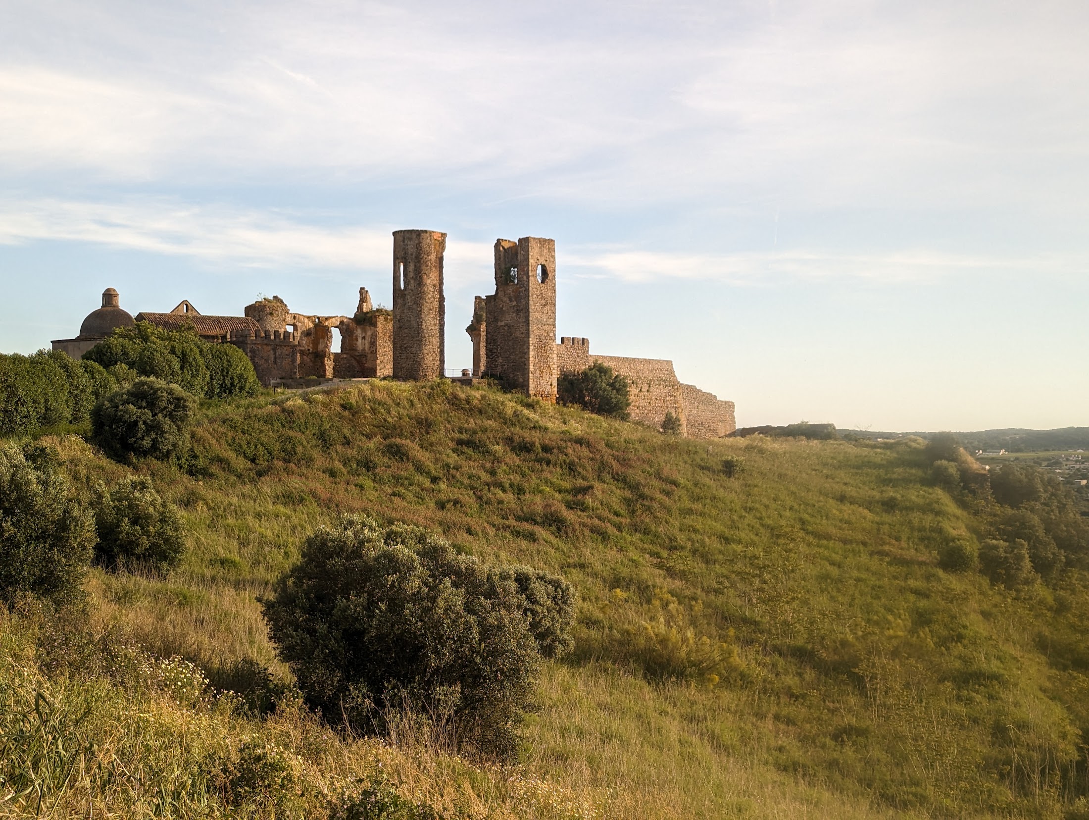 Ruínas do castelo de Montemor-o-Novo ao entardecer, sobre a colina verde